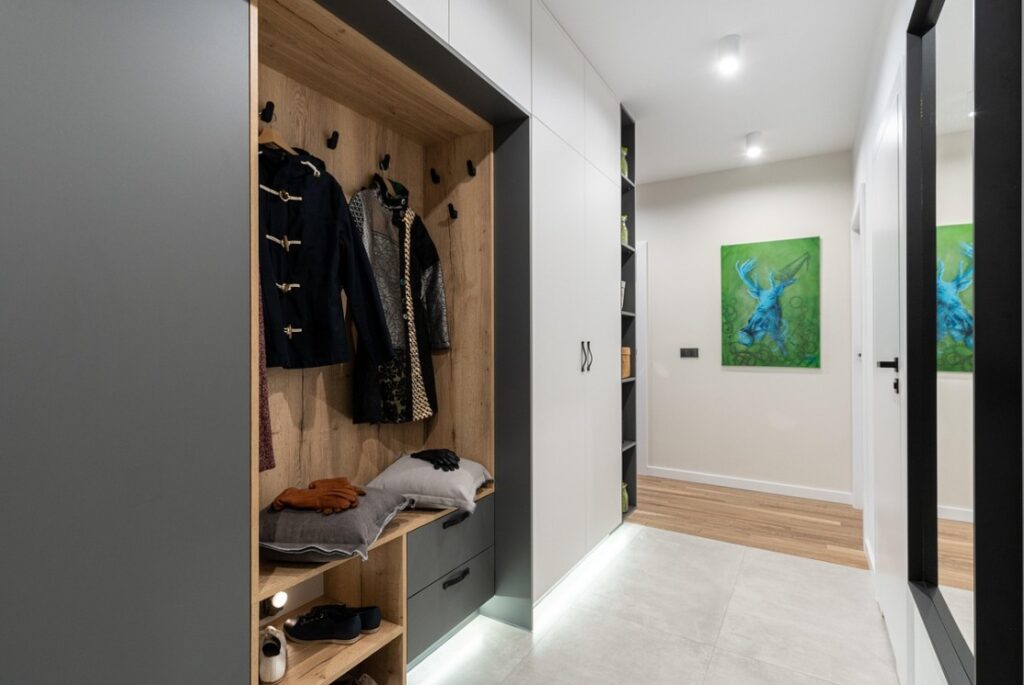 Strakke hal met ingebouwde garderobekast, houten accenten en moderne verlichting