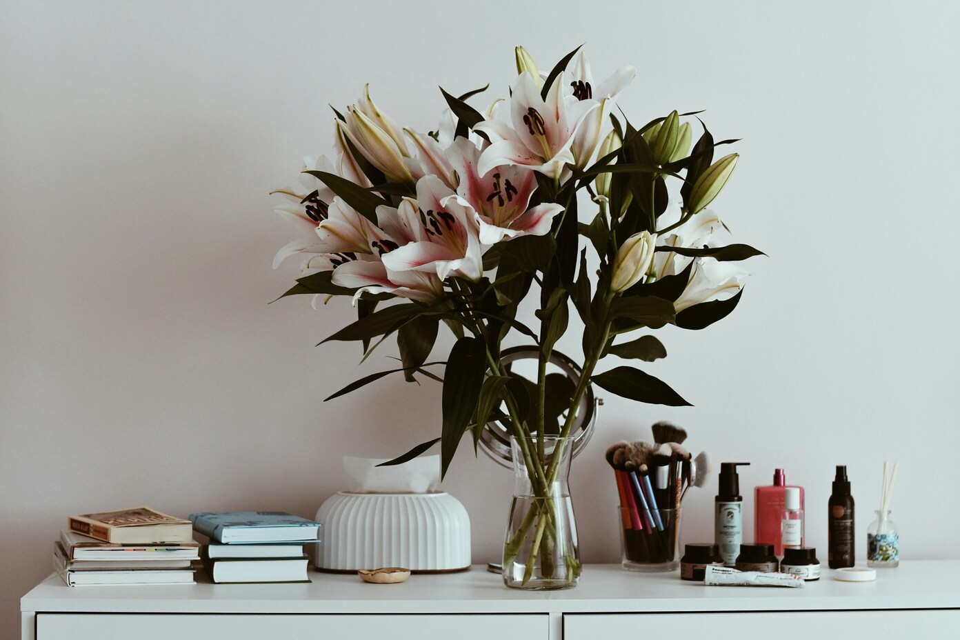 Vaas bloemen op een kast met boeken en spullen voor beautygewoontes