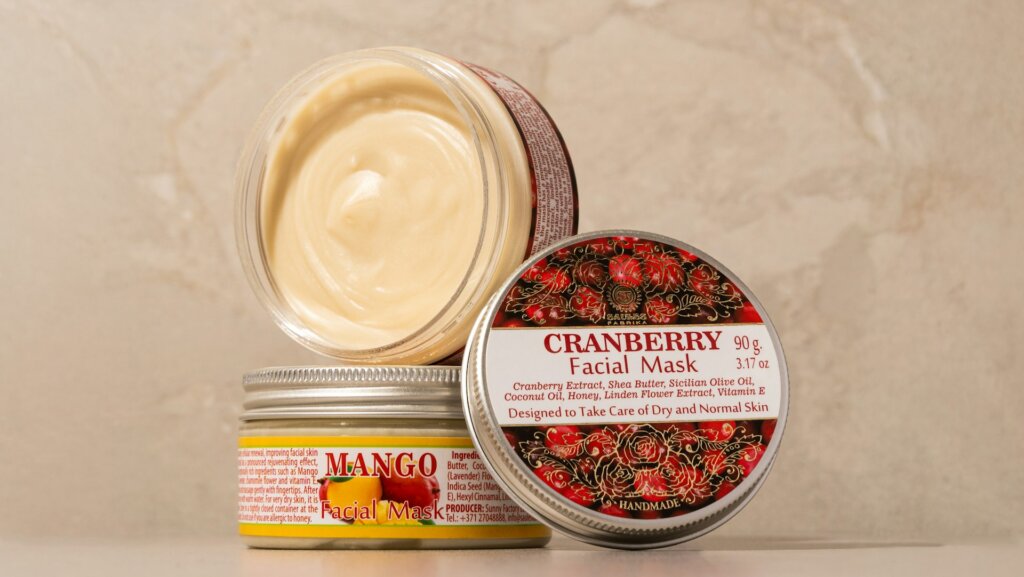Twee potjes natuurlijke gezichtsmaskers met mango en cranberry voor voedende huidverzorging.