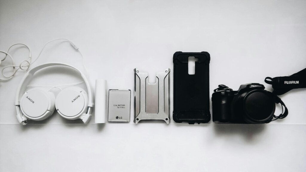 Minimalistische tech-accessoires in wit en zwart, inclusief hoofdtelefoon, camera en telefoonhoesje.