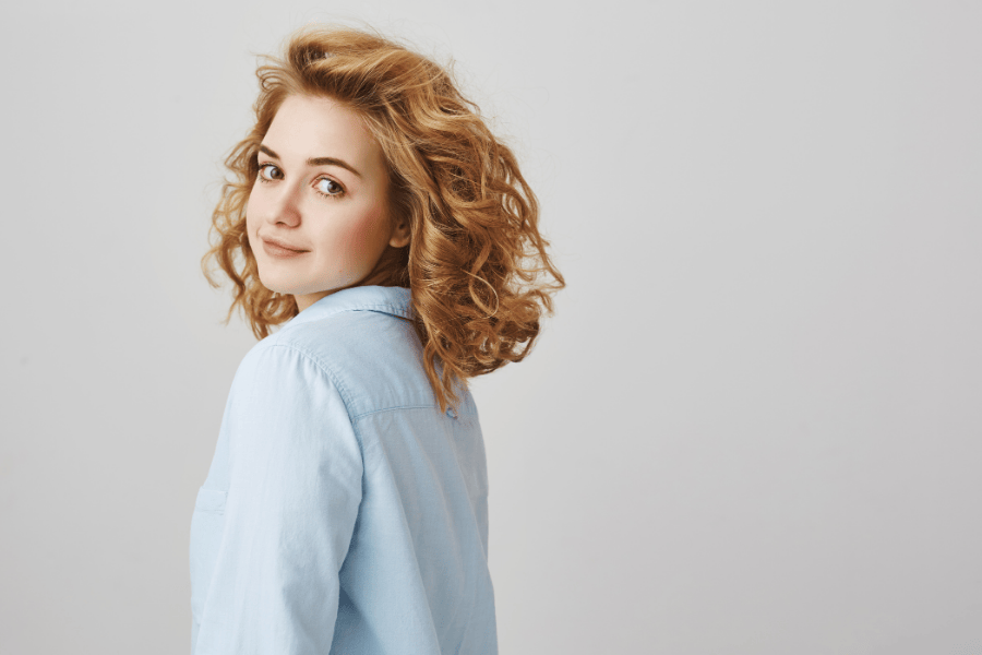 Vrouw blauwe blouse krullend haar