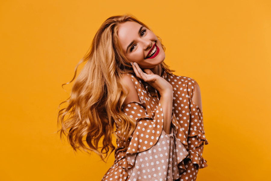 Vrouw oranje blouse waves haar rode lippenstift