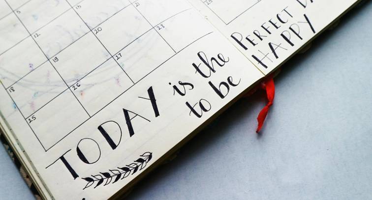 Open agenda met maandkalender en handgeschreven tekst "Today is the perfect day to be happy"