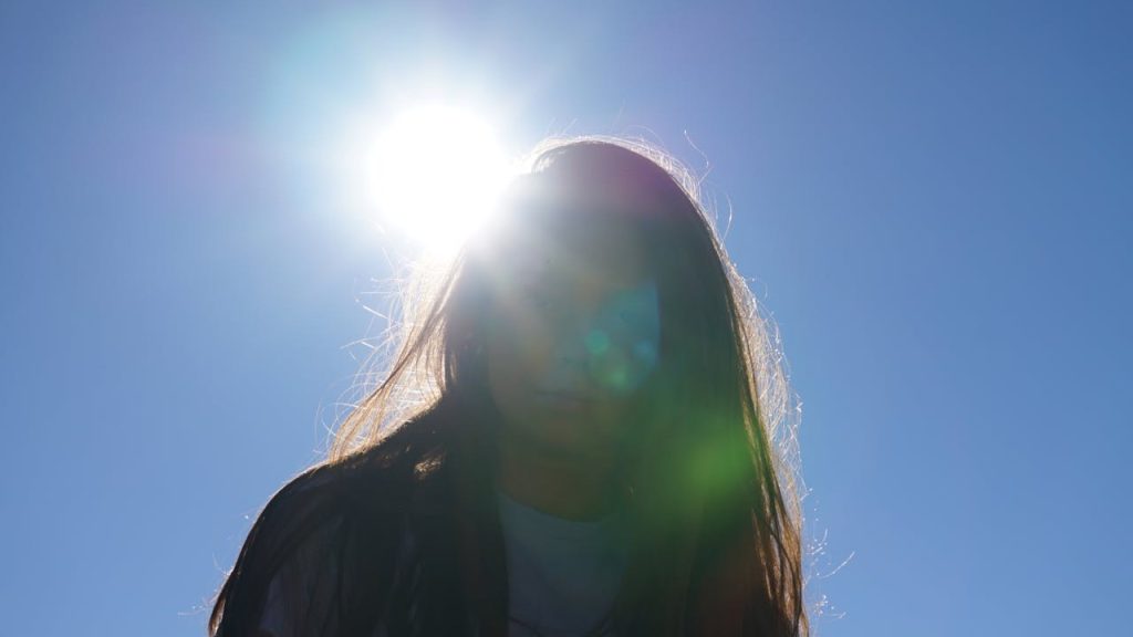 Vrouw buiten met zon op achtergrond