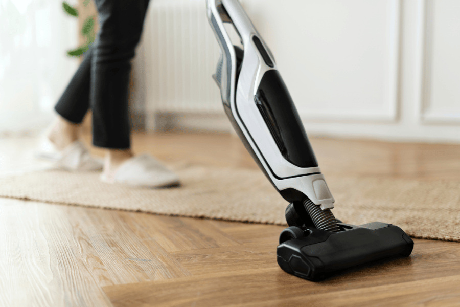 Vrouw witte sloffen beige mat zwarte steelstofzuiger