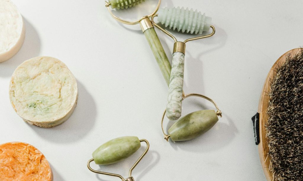 Groene jade rollers en natuurlijke verzorgingsproducten op een lichte ondergrond