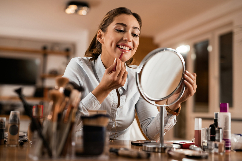Vrouw brengt lipliner aan voor een verzorgde beautylook tijdens een drukke dag.
