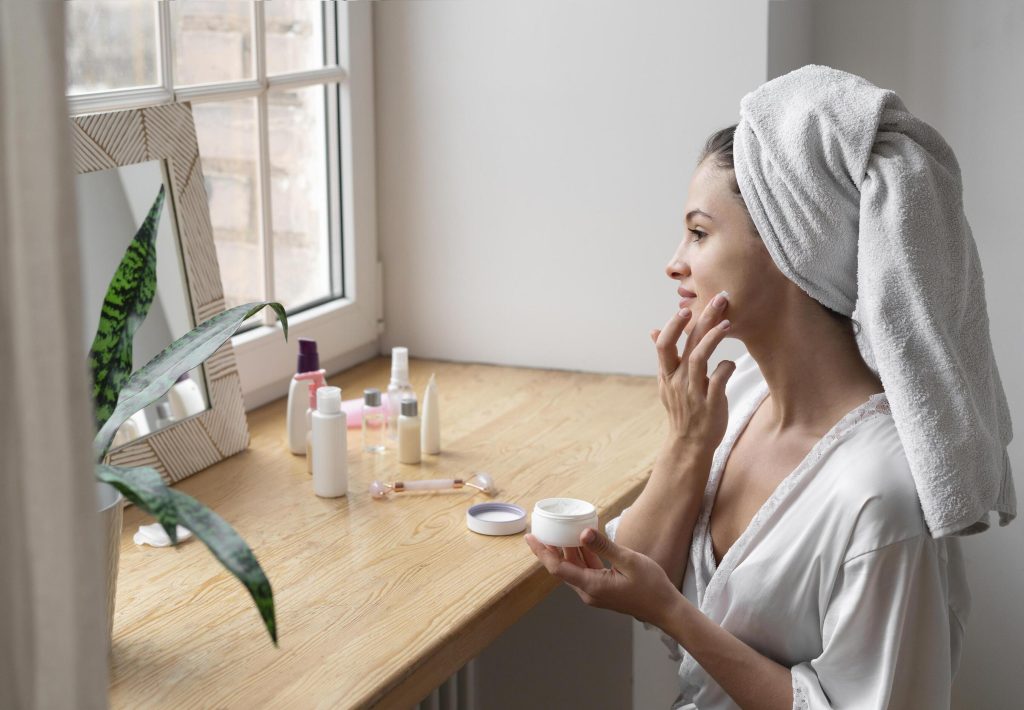 Vrouw brengt gezichtscrème aan tijdens een ontspannen selfcare routine thuis.