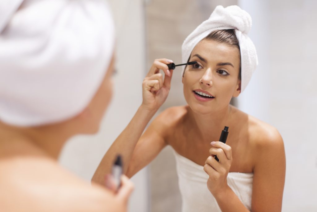 vrouw doet mascara op haar wimpers